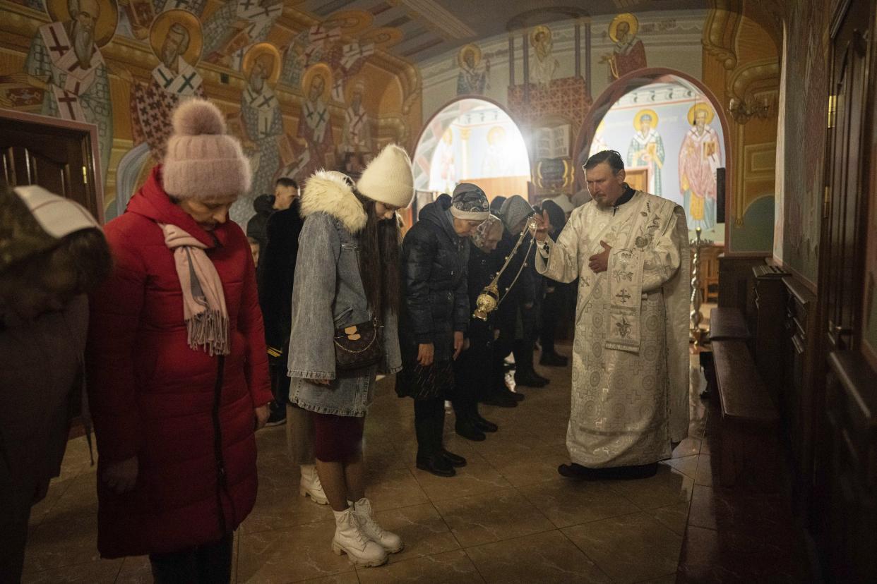 An Orthodox priest blesses believers during Christmas church service in Kostyantynivka, Ukraine, Friday, Jan. 6, 2023. (AP Photo/Evgeniy Maloletka)