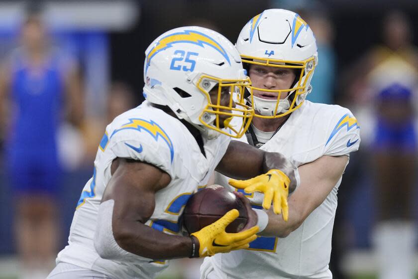 Los Angeles Chargers quarterback Easton Stick, right, hands off to running back Joshua Kelley.