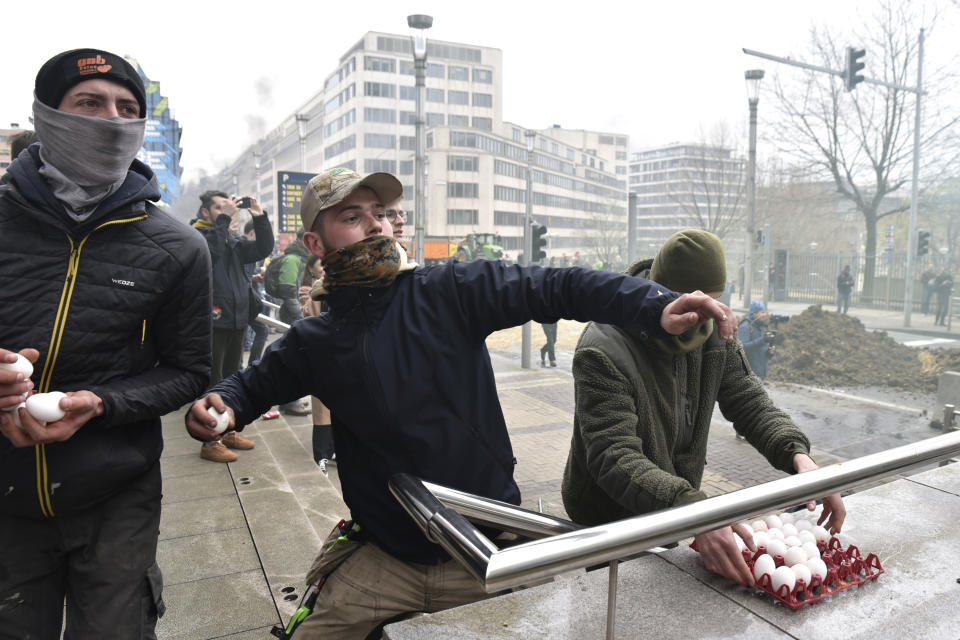 Protestors throw eggs at police during a demonstration outside the European Council building in Brussels, Tuesday, March 26, 2024. Dozens of tractors sealed off streets close to European Union headquarters where the 27 EU farm ministers are meeting to discuss the crisis in the sector which has led to months of demonstrations across the bloc. (AP Photo/Harry Nakos)