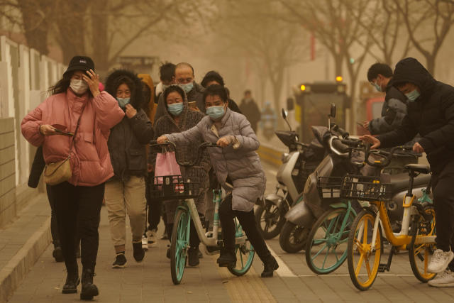 Residents make their way through a sandstorm in Beijing, Monday, March 15, 2021. The sandstorm brought a tinted haze to Beijing's skies and sent air quality indices soaring on Monday. (AP Photo/Ng Han Guan)
