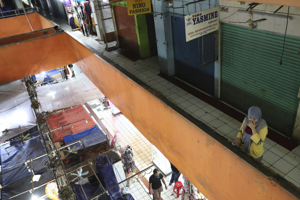 A woman stands at a quiet market in Jakarta, Indonesia, Friday, April 10, 2020. Authorities began stricter measures to halt the new coronavirus' spread in Indonesia's capital Friday, with its normally congested streets empty after death toll spiked in the past week. (AP Photo/Achmad Ibrahim)