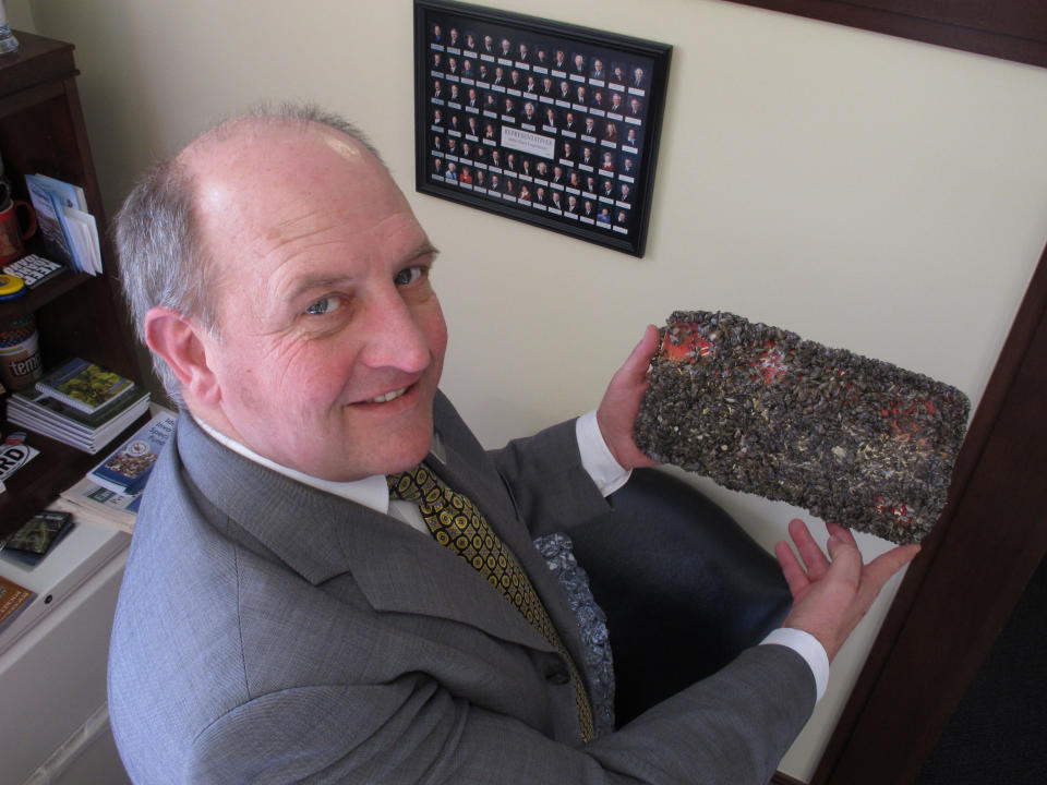 FILE - In this Feb. 7, 2012, file photo, Idaho State Rep. Eric Anderson poses in his offices in the Idaho Capitol in Boise with an Idaho license plate he left for six months in Lake Mead near Las Vegas to be encrusted with quagga mussels. A regional power planning group from Idaho, Oregon, Washington and Montana is pursuing $2 million from the federal government to help fend off the menace of invasive mussels that have clogged Colorado River reservoirs since 2007. These states and others say they're frustrated by the number of boats that continue to come from Lake Mead in Nevada and Arizona over their borders infested with quagga and zebra mussels. (AP Photo/John Miller, File)