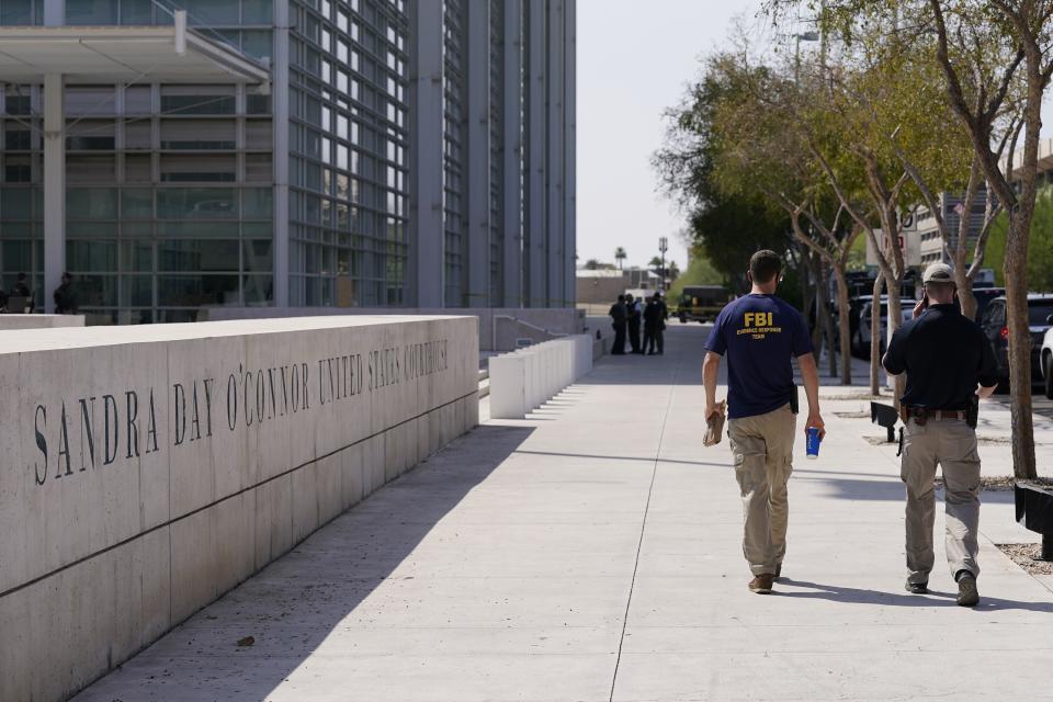 Federal law enforcement personnel walk past the Sandra Day O'Connor Federal Courthouse Tuesday, Sept. 15, 2020, in Phoenix. A drive-by shooting wounded a federal court security officer Tuesday outside the courthouse in downtown Phoenix, authorities said. The officer was taken to a hospital and is expected to recover, according to city police and the FBI, which is investigating. (AP Photo/Ross D. Franklin)