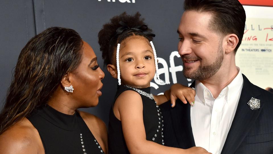 Proud parents Serena and Alexis with their daughter at a red carpet event, Alexis is holding Olympia in his arms