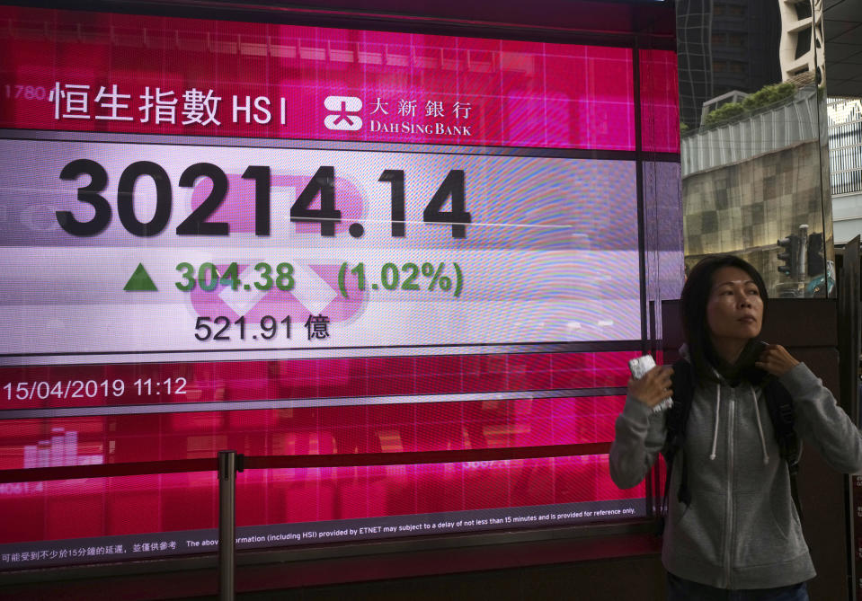 A woman walks past an electronic board showing Hong Kong share index outside a local bank in Hong Kong, Monday, April 15, 2019. Asian markets were broadly higher Monday on signs that the U.S. and China were closing in on a trade deal after months of negotiations.(AP Photo/Vincent Yu)