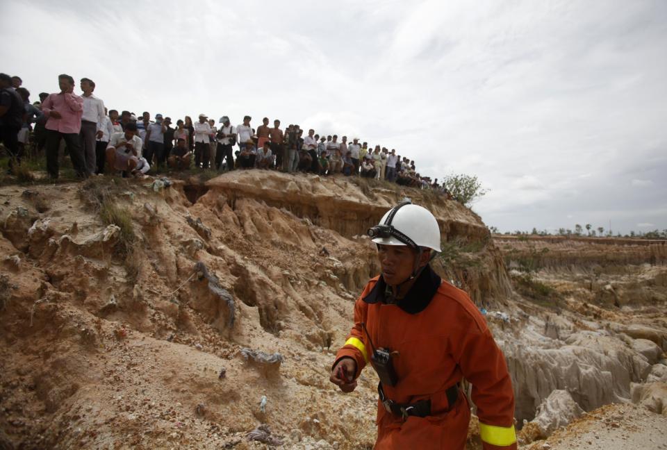 A rescue worker walks at the site where a Cambodian military helicopter crashed on the outskirts of Phnom Penh July 14, 2014. The military helicopter crashed on Monday, killing five and injured one, police told Reuters. A Cambodian air force official said authorities are still investigating the cause of the crash. (REUTERS/Samrang Pring)