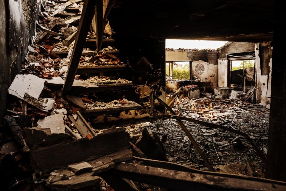 Debris covering stairs and the floor of a scorched house with roof and windows blown out