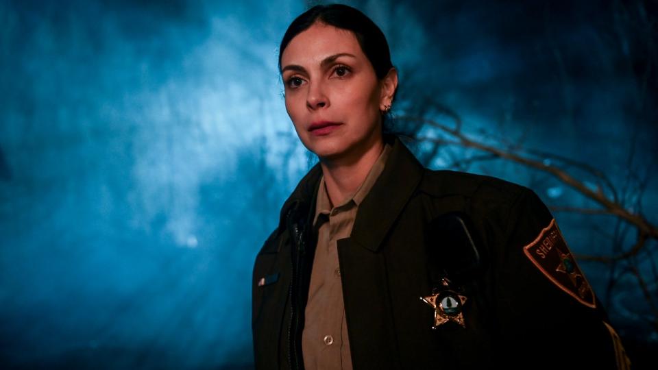 Morena Baccarin as Mickey standing in front of trees on Fire Country.