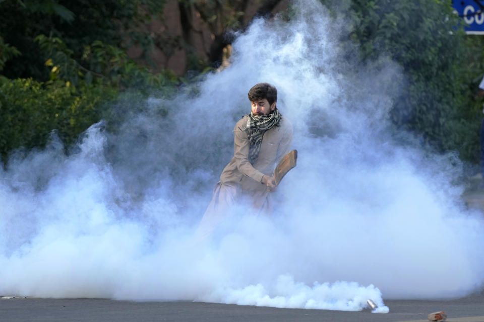 A supporter of Pakistan's former Prime Minister Imran Khan removes a tear gas shell fired by police to disperse them protesting against the arrest of their leader, in Lahore, Pakistan, Tuesday, May 9, 2023. Khan was arrested Tuesday as he appeared in a court in the country’s capital, Islamabad, to face charges in multiple graft cases. Security agents dragged Khan outside and shoved him into an armored car before whisking him away. (AP Photo/K.M.Chaudary)