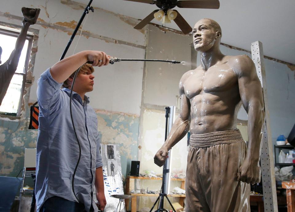 Ben Calhoun, an apprentice of Caleb O'Connor, sprays water on the one-to-one life-size sculpture of Deontay "Bronze Bomber" Wilder, the World Heavyweight Champion, sculpted by O'Connor, before the start of a press conference at O'Connor Art Studio in Tuscaloosa Thursday, March 16, 2017.   [Staff Photo/Erin Nelson]