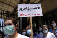 A nurse holds an Arabic placard that reads: "Doctors are migrating, we cannot continue like this," as he protests with other medical workers and doctors the deteriorating economic conditions, outside the Central Bank, in Beirut, Lebanon, Thursday, May 26, 2022. The syndicates of doctors in Beirut and the North as well as the Syndicate of Private Hospital Owners declared a two-day general strike Thursday and Friday. (AP Photo/Hussein Malla)