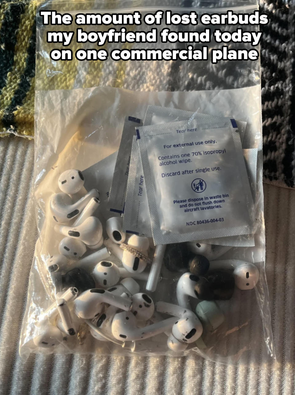 A clear plastic bag filled with several pairs of used earbud headphones. 