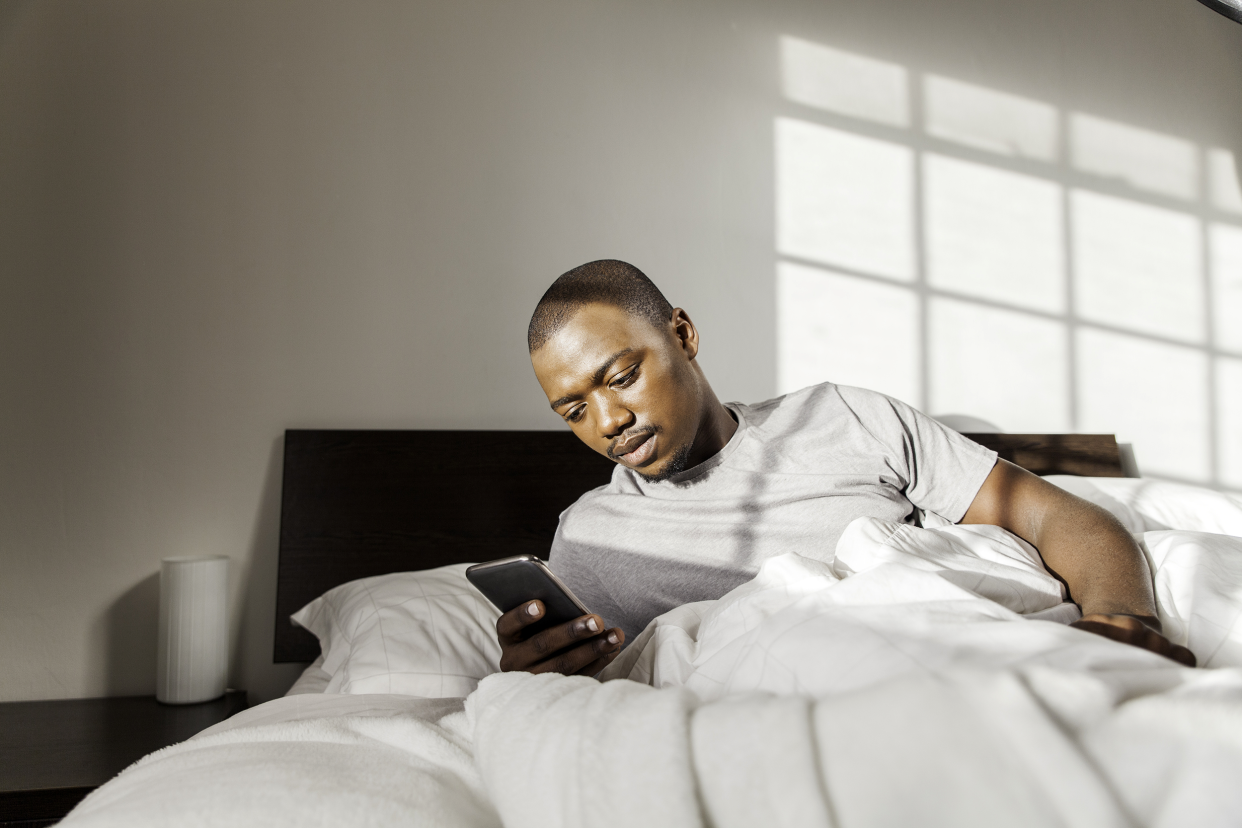 Man waking up and using his phone in bed