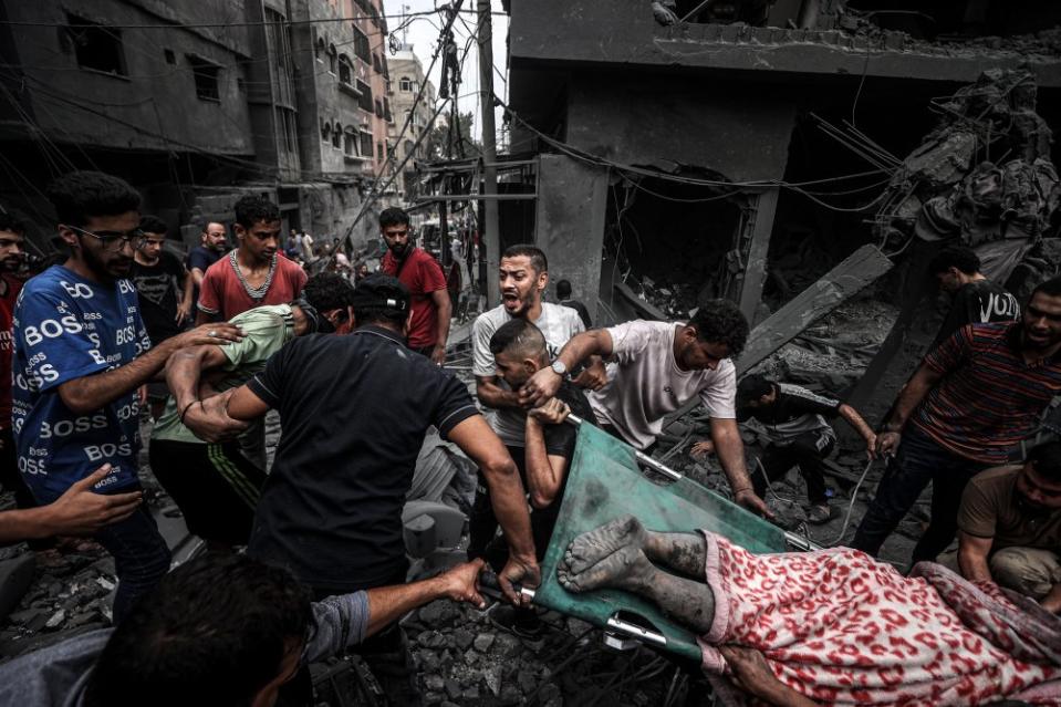 People carry injured and dead Palestinians from the rubbles of buildings as civil defense teams and civilians conduct search and rescue operations after Israeli attacks on Al-Shati refugee camp in Gaza City, on Oct. 27.<span class="copyright">Ali Jadallah—Anadolu/Getty Images</span>