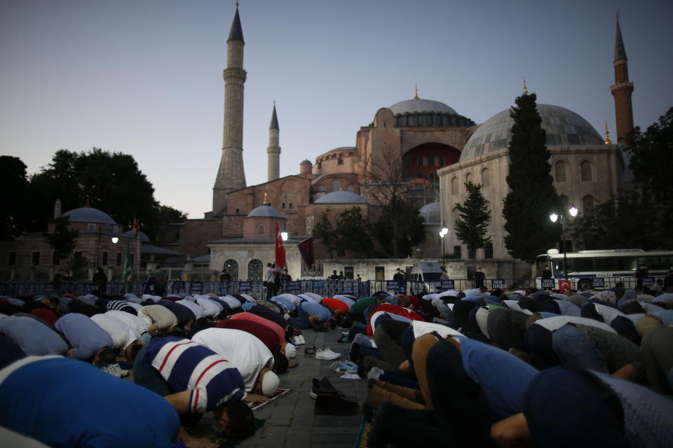 Muslims offer their evening prayers outside the Byzantine-era Hagia Sophia, one of Istanbul's main tourist attractions in the historic Sultanahmet district of Istanbul, following Turkey's Council of State's decision, Friday, July 10, 2020. Turkey's highest administrative court issued a ruling Friday that paves the way for the government to convert Hagia Sophia - a former cathedral-turned-mosque that now serves as a museum - back into a Muslim house of worship. The Council of State threw its weight behind a petition brought by a religious group and annulled a 1934 cabinet decision that changed the 6th century building into a museum.(AP Photo/Emrah Gurel)