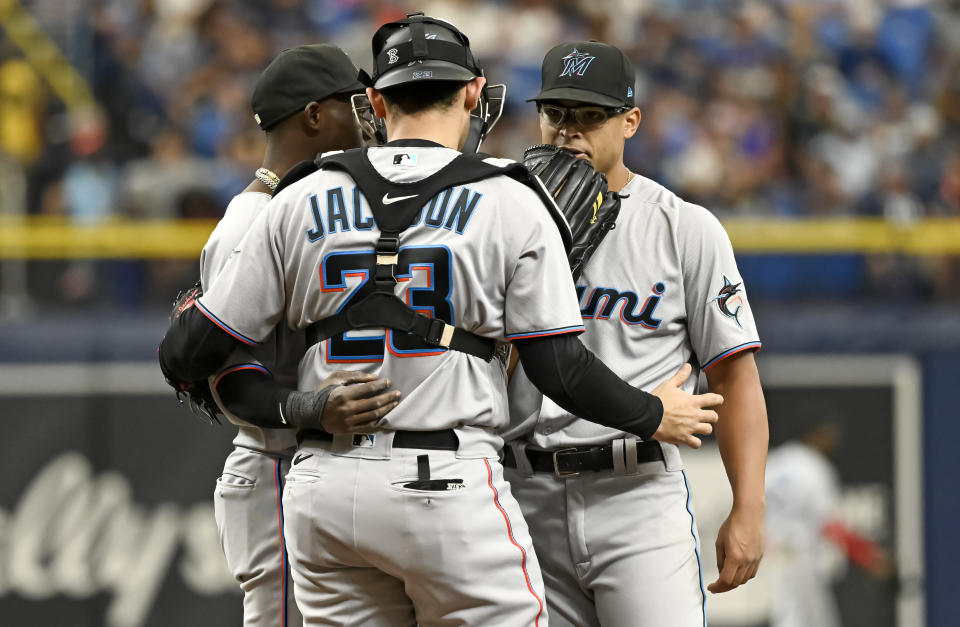 Miami Marlins catcher Alex Jackson (23) and shortstop Jazz Chisholm Jr., left, talk with starter Jesus Luzardo, right, on the mound during the first inning of a baseball game against the Tampa Bay Rays, Sunday, Sept. 26, 2021, in St. Petersburg, Fla. (AP Photo/Steve Nesius)