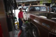 In this Oct. 8, 2019 photo, a gas station attendant fills a truck's tank in San Antonio de los Altos on the outskirts of Caracas, Venezuela. Amid the economic crash, President Nicolas Maduro has not substantially raised gas prices, a strategy that was probably reinforced after violent protests recently forced the president of Ecuador to back off plans to end fuel subsidies there. (AP Photo/Ariana Cubillos)