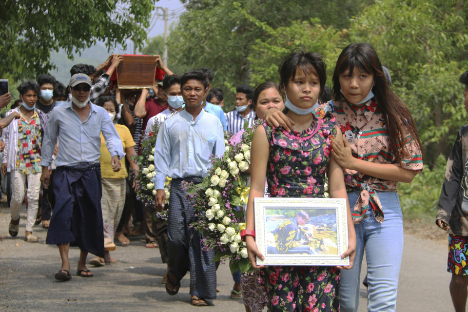 In this April 1, 2021 photo provided by Dawei Watch news outlet, Hnin Twel Tar Aung holds an image of her 17-year old boyfriend, Kyaw Min Latt, followed by his mother, Maw Maw Oo, partially obscured; and father, Soe Soe Latt, while walking in front of Kyaw Min Latt's coffin during a funeral procession in Dawei, Myanmar. Soe Soe Latt, who learned of his son's shooting from social media, rushed to the military hospital to see him. “He was wounded a lot. ... He opened his eyes when we were at the hospital but could not say any words.” (Dawei Watch via AP)