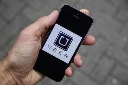 A photo illustration shows the Uber app logo displayed on a mobile telephone, as it is held up for a posed photograph in central London, Britain October 28, 2016. REUTERS/Toby Melville/Illustration