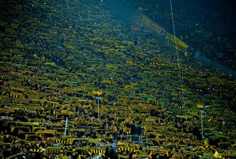 Fans show their scarves as a sign of respect following the death of a fan during the German first division Bundesliga football match Borussia Dortmund v 1 FSV Mainz 05 in Dortmund, on March 13, 2016