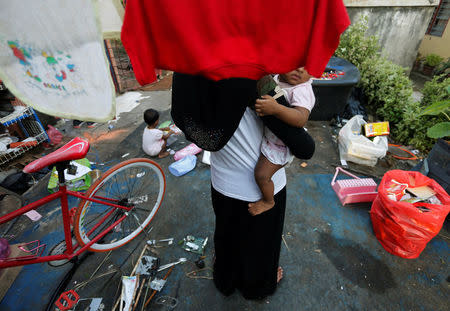 A Rohingya child bride who ran away from her husband carries her sister outside a shack she shares with her mother and siblings, on the outskirts of Kuala Lumpur, Malaysia, February 9, 2017. Picture taken February 9, 2017. REUTERS/Lai Seng Sin