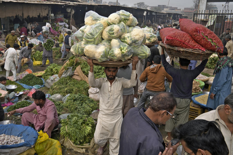 Laborers work at a wholesale vegetable and fruit market in Lahore, Pakistan, Friday, Feb. 17, 2023. Many laborers are worried how they will survive after the government advanced a bill to raise 170 billion rupees in tax revenue. That could worsen impoverished Pakistan's economic outlook as it struggles to recover from devastating summer floods and a wave of violence. (AP Photo/K.M. Chaudary)
