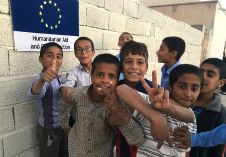 Afghan refugee boys pose next to the EU humanitarian aid sign posted outside their school in the Bardsir settlement for Afghan refugees in Kerman province, Iran, October 22, 2016. Picture taken October 22, 2016. REUTERS/Gabriela Baczynska