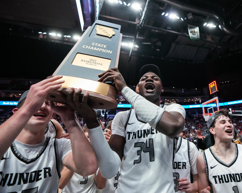 Grand View Christian junior Noah John (35) and senior Daniel Tobiloba (34) hold their teams championship trophy after defeating North Linn in the class 1A championship game of the Iowa high school boys state basketball tournament.