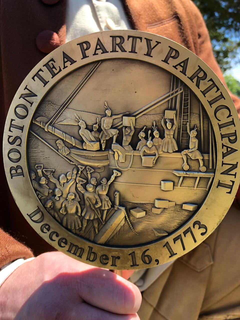 Ryan Stack, portraying Capt. Joseph Bassett poses with the Tea Party commemorative medal Wednesday at the grave of Capt. Bassett after a short ceremony in Yarmouth Port.