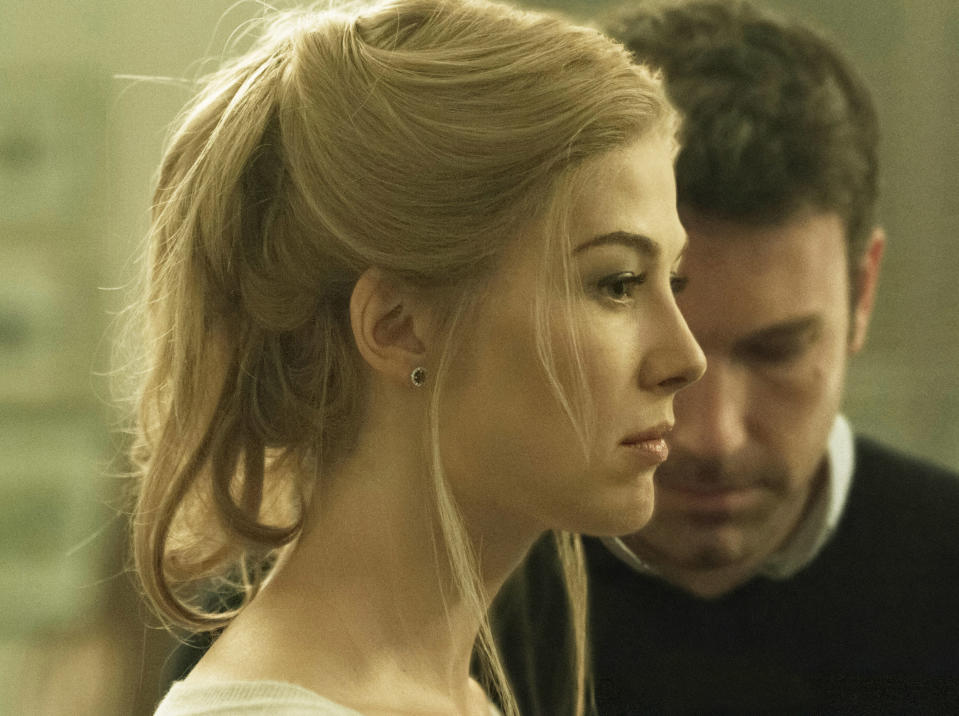 Rosamund Pike blankly stares forward while Ben Affleck looks at the ground behind her