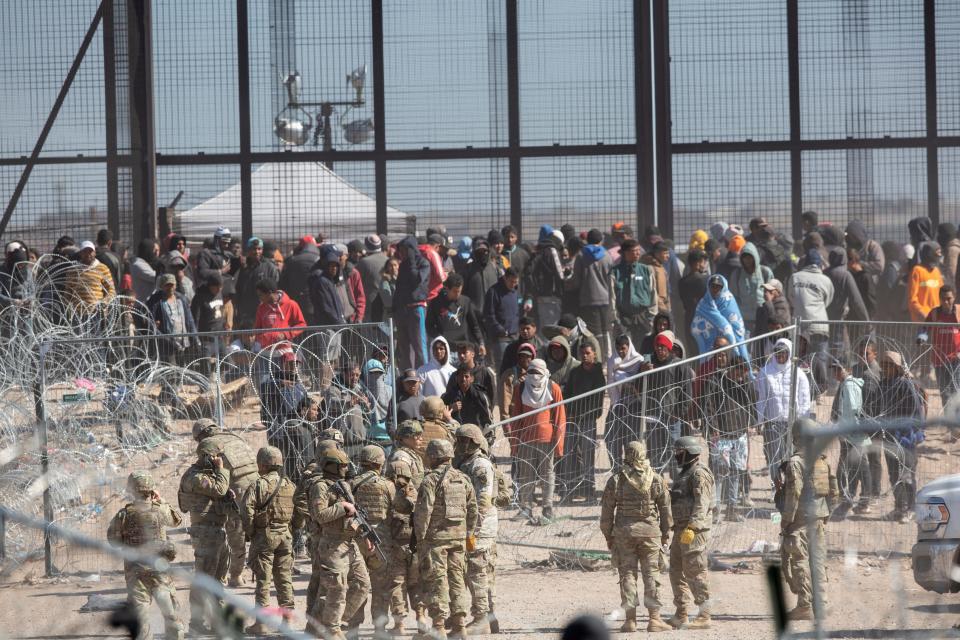Migrants seeking to turn themselves into U.S. Border Patrol agents line up near the border fence in El Paso on March 21. The migrants had earlier breached razor wire barriers set up on the north side of Rio Grande Texas National Guard troops.