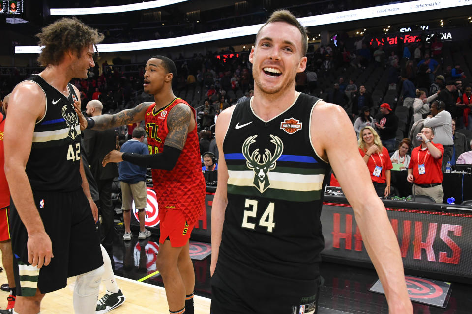 Milwaukee Bucks guard Pat Connaughton (24) leaves the court as center Robin Lopez (42) and Atlanta Hawks forward John Collins converse after an NBA basketball game Friday, Dec. 27, 2019, in Atlanta. (AP Photo/John Amis)