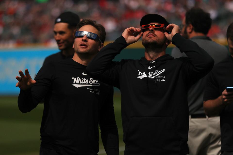 Tanner Banks #57 and Paul DeJong #29 of the Chicago White Sox look up at the total solar eclipse before the game against the Cleveland Guardians at Progressive Field on April 08, 2024 in Cleveland, Ohio.