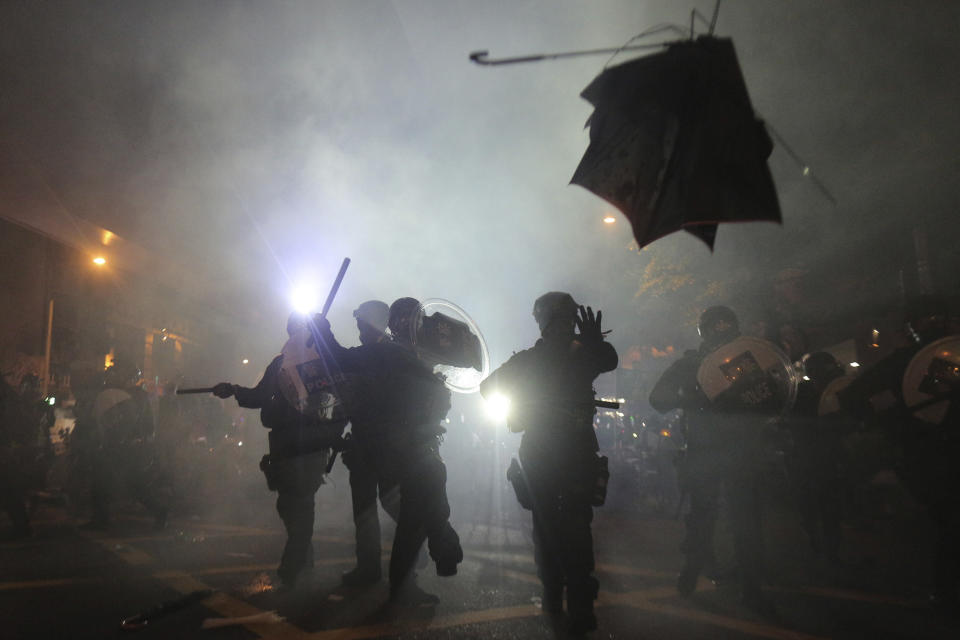 A broken umbrella flies by near riot police, during confrontation with protesters in Hong Kong Sunday, July 21, 2019. Hong Kong police launched tear gas at protesters Sunday after a massive pro-democracy march continued late into the evening. The action was the latest confrontation between police and demonstrators who have taken to the streets to protest an extradition bill and call for electoral reforms in the Chinese territory. (Andy Lo/HK01 via AP)