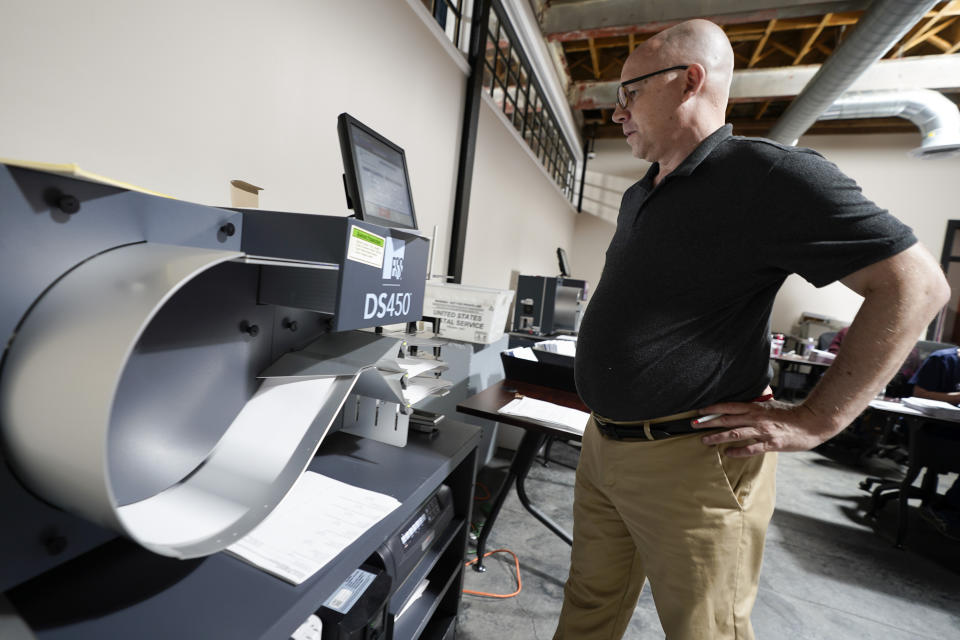 Mercer County, Pa., Director of Elections Thad Hall stands before an optical scanner as it counts ballots.