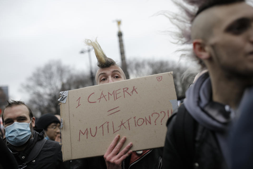 A demonstrator holds a poster during a protest, Saturday, Dec.12, 2020 in Paris. Protests are planned in France against a proposed bill that could make it more difficult for witnesses to film police officers. (AP Photo/Lewis Joly)