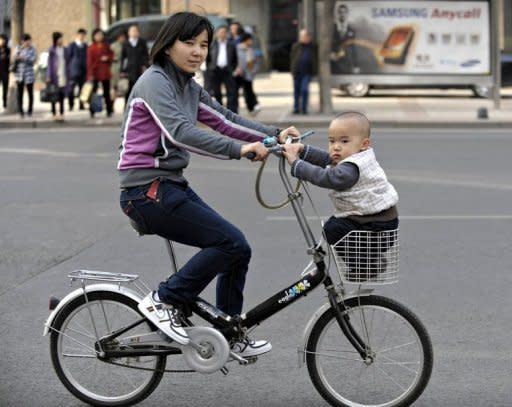 A child sitting in a bicycle basket along a street in Beijing, on October 18. China's one-child policy has prevented almost half a billion births but has turned into a demographic time bomb as the population ages, storing up huge economic and social problems for the country