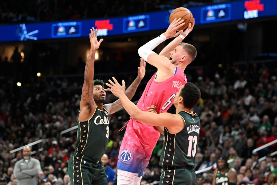Kristaps Porzingis (middle) is heading to the Celtics while Boston is shipping Marcus Smart (left) to the Memphis Grizzlies in a three-team deal.