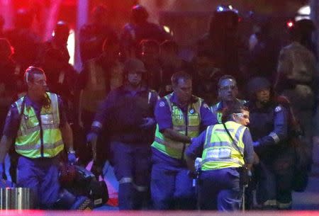 Heavily armed policemen watch as paramedics remove injured people away from the Lindt cafe, where hostages were being held, at Martin Place in central Sydney December 16, 2014. REUTERS/David Gray
