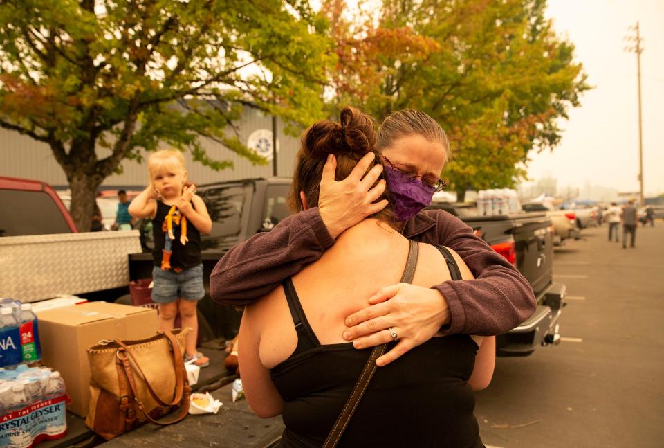 Lindsie Cline (right) hugs her sister-in-law Brittany Cline from Leaburg, Ore. at an evacuation center at Springfield High in Springfield, Ore. on  Sept. 10, 2020 after their families fled the flames of the Holiday Farm Fire.