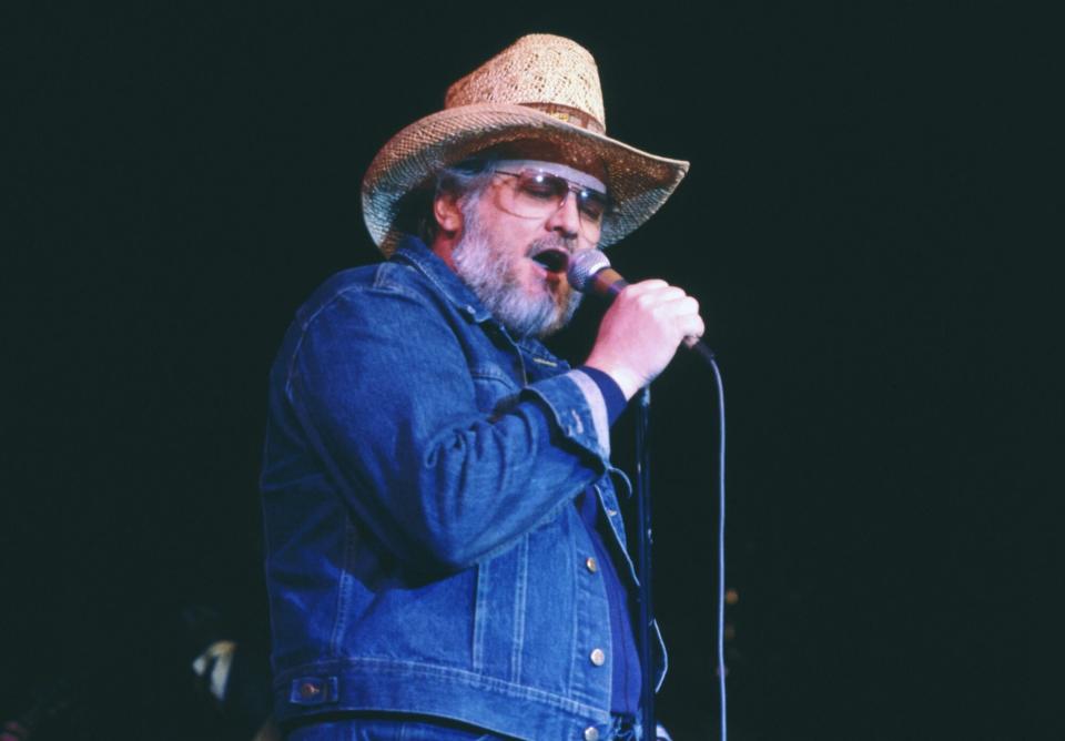 Canadian entertainer, Ronnie Hawkins, wearing cowboy-type clothing and singing to live audience.