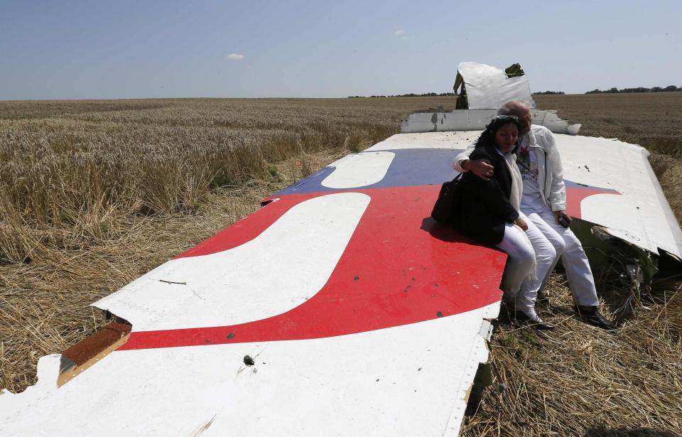 George and Angela Dyczynski sit on a piece of wreckage of the downed Malaysia Airlines Flight MH17, during their visit to the crash site near the village of Hrabove (Grabovo), in Donetsk region in this July 26, 2014 file photo. The 19,500 staff of Malaysia Airlines (MAS) face a new ordeal - a quarter of them may lose their jobs at the unprofitable airline, hit by two jet disasters this year. Flight MH370 remains untraced since its disappearance en route from Kuala Lumpur to Beijing in March. REUTERS/Sergei Karpukhin (UKRAINE - Tags: POLITICS DISASTER TRANSPORT CIVIL UNREST)
