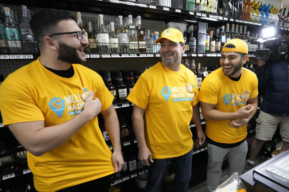 Store co-owner Nidal Khalil, center, smiles with son Jonathan Khalil, left, and nephew Chris Khalil, right, after putting on T-shirts at the Midway Market & Liquor store, Thursday, Oct. 12, 2023, in Frazier Park, Calif., where a winning Powerball lottery ticket was sold. A player in California won a $1.765 billion Powerball jackpot Wednesday night, ending a long stretch without a winner of the top prize. (AP Photo/Marcio Jose Sanchez)