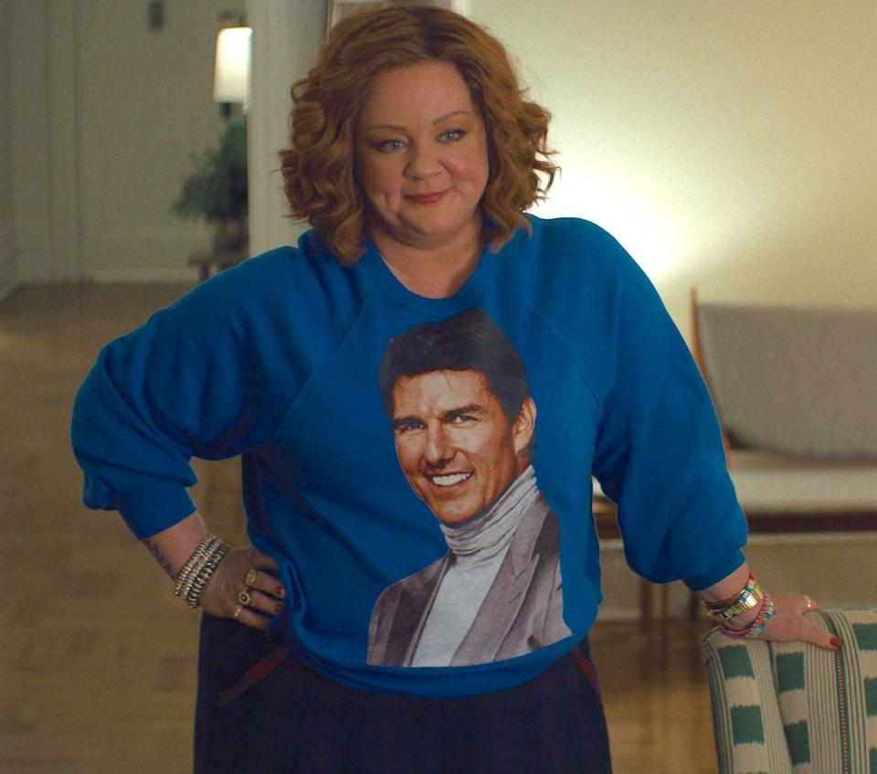 melissa mccarthy in genie, a woman smiles as she wears a blue jumper with tom cruise's face on it