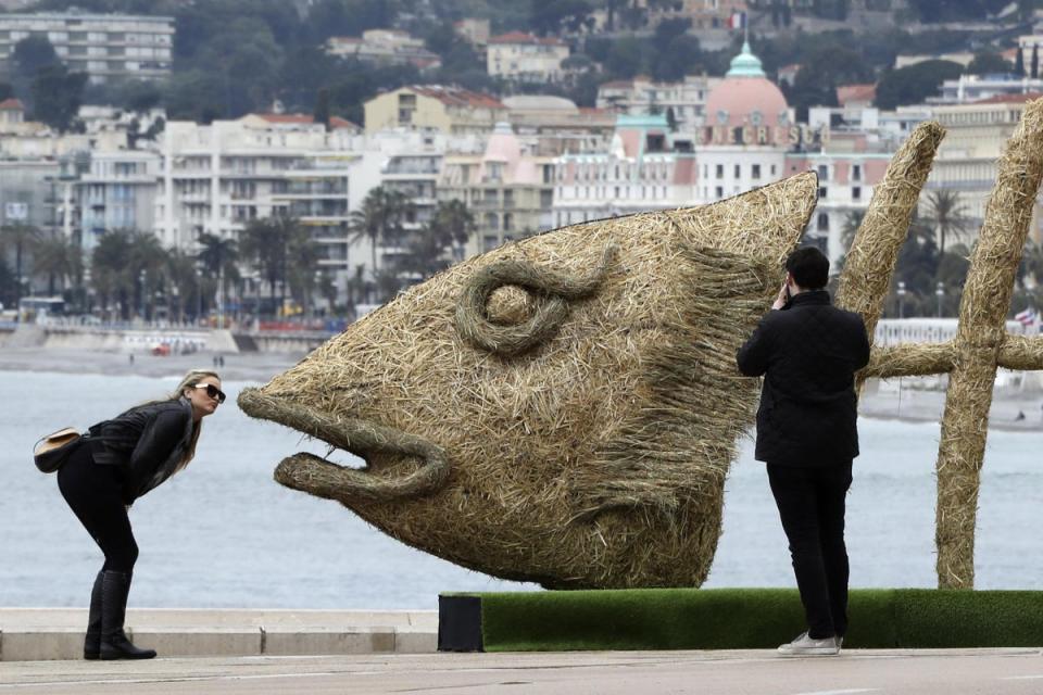 People take pictures of a giant straw fish in Nice, France, that was installed on April Fools' Day (Valery Hache / AFP / Getty Images)