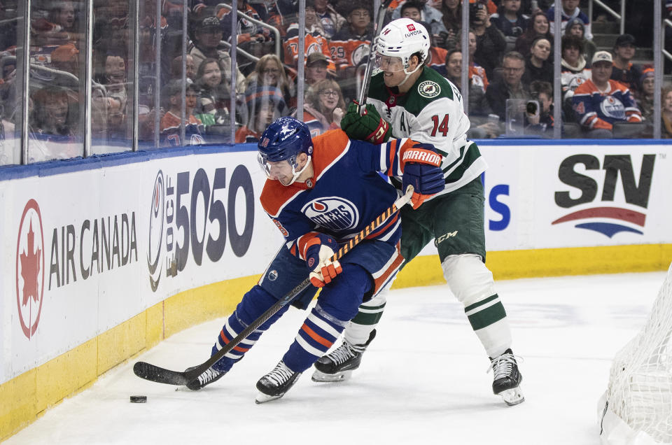 Minnesota Wild's Joel Eriksson Ek (14) and Edmonton Oilers' Zach Hyman (18) compete for the puck during the second period of an NHL hockey game Friday, Feb. 23, 2024, in Edmonton, Alberta. (Jason Franson/The Canadian Press via AP)