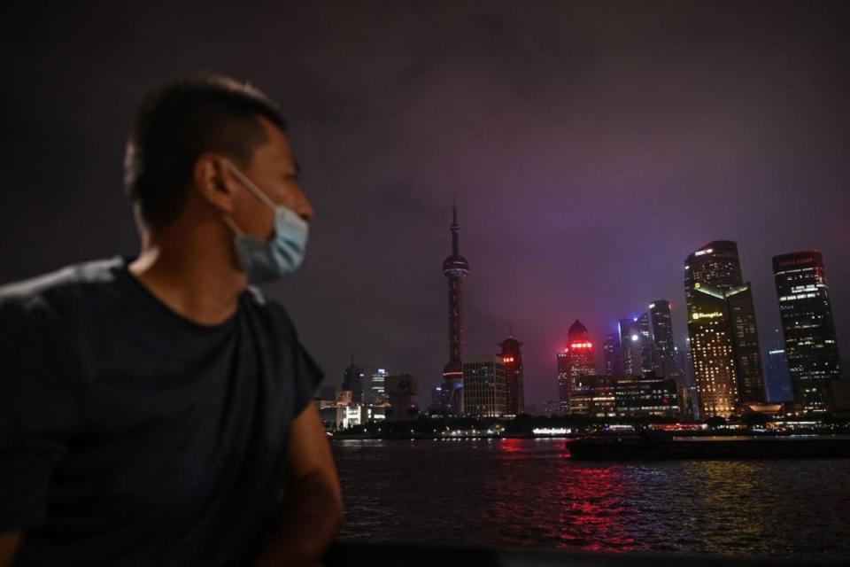 A man looks out from the Bund promenade along the Huangpu River as decorative lights are switched off as a measure to save energy in Shanghai (AFP via Getty Images)