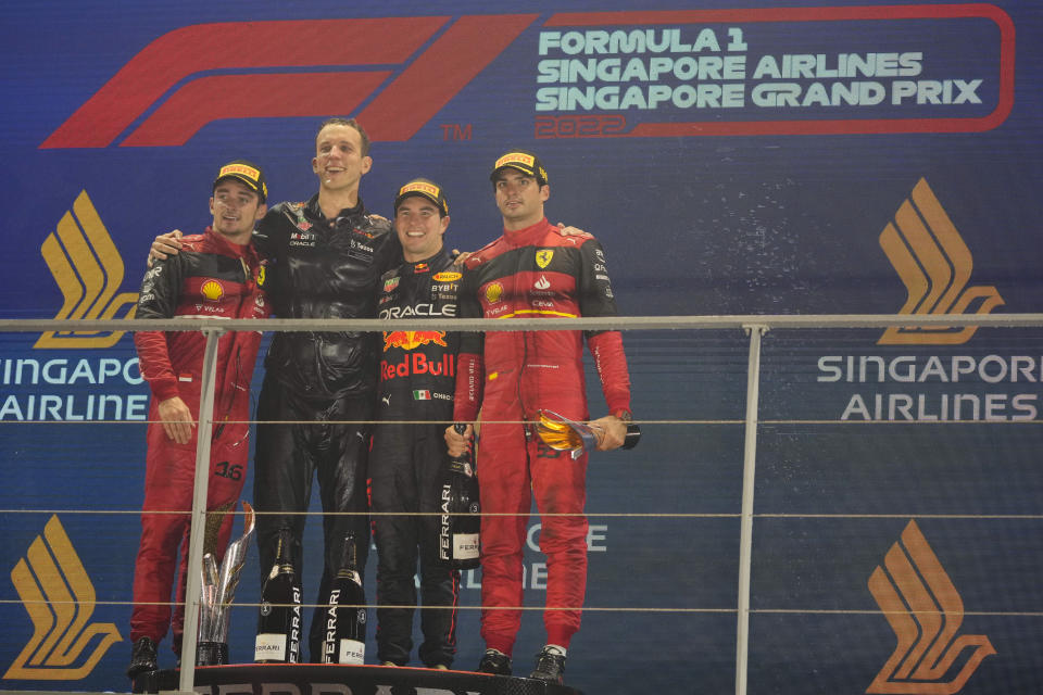 Red Bull driver Sergio Perez of Mexico, second from right, poses as he wins the Singapore Formula One Grand Prix beside second place Ferrari driver Charles Leclerc, left, of Monaco and third place Ferrari driver Carlos Sainz, right, of Spain at the Marina Bay City Circuit in Singapore, Sunday, Oct. 2, 2022. (AP Photo/Vincent Thian)