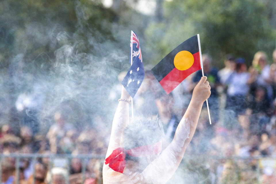 Man hold Aboriginal flag and Australian flag during Australia/ Invasion Day march