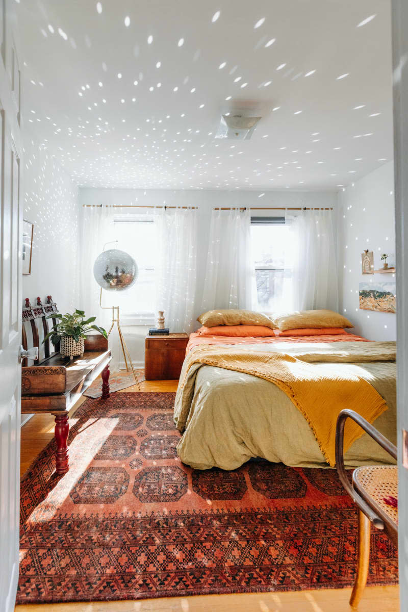 Light reflects off disco ball in white bedroom with rust accents.